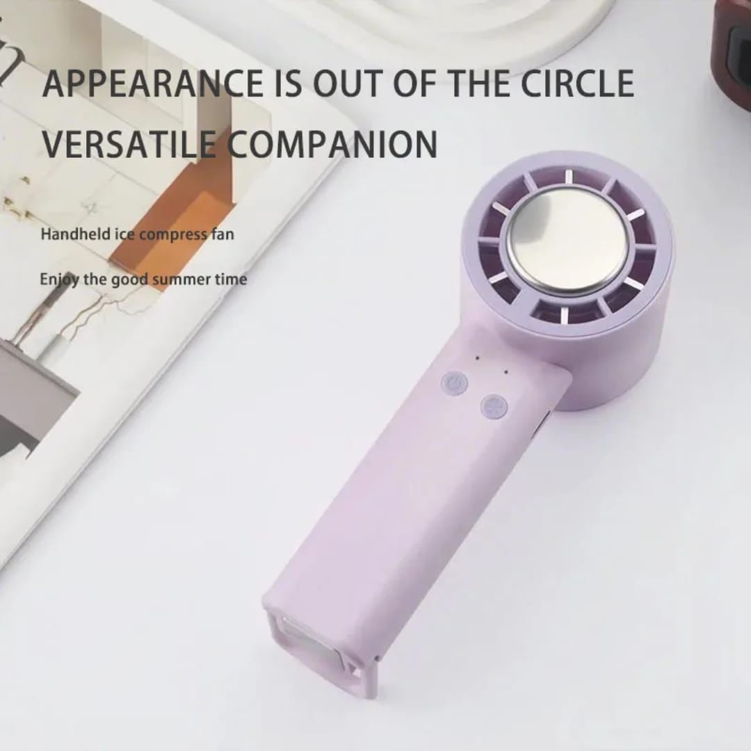 A white or pink handheld mini portable rechargeable fan with a built-in stand, blowing a cool breeze. The fan is lightweight and has a modern, minimalist design.