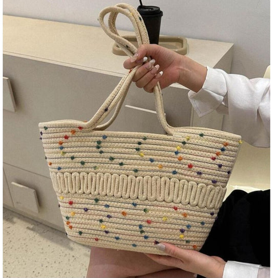 Hand holding a woven bag with colorful dots in an indoor setting